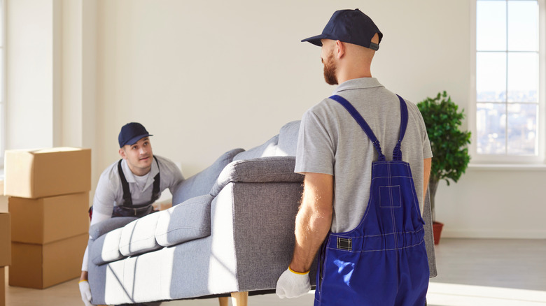 Two males moving a new sofa into a home