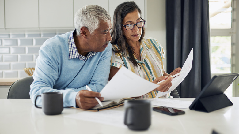 senior couple checking paperwork at kitchen table