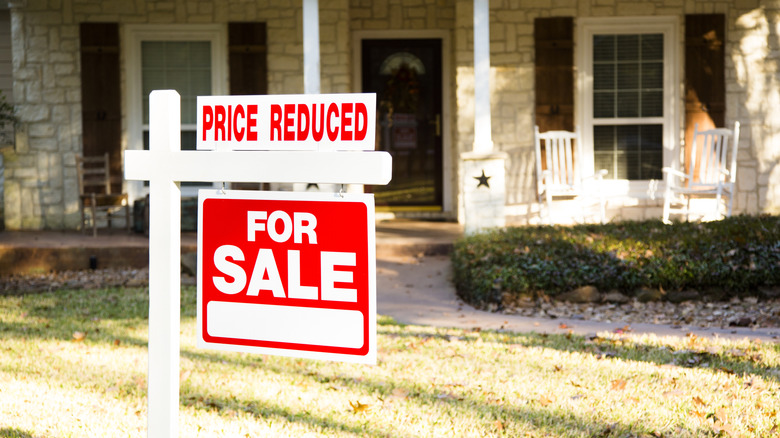 A suburban home with a For Sale sign outside
