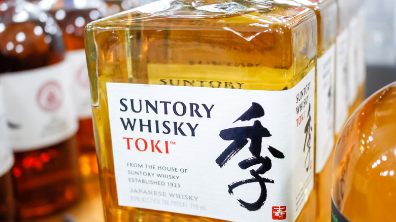 A closeup of a Suntory Whisky Toki bottle label with other bottles in the background.