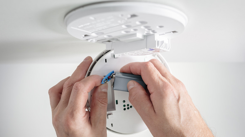 Person installing a battery in a smoke detector