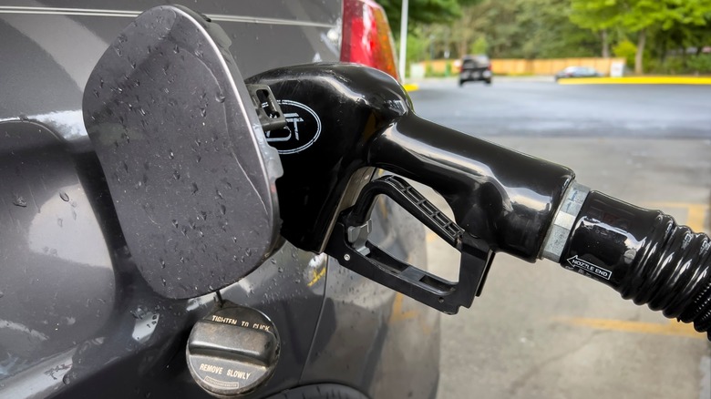 Close-up of a gas pump nozzle inserted into a car's fuel tank with the fuel door open