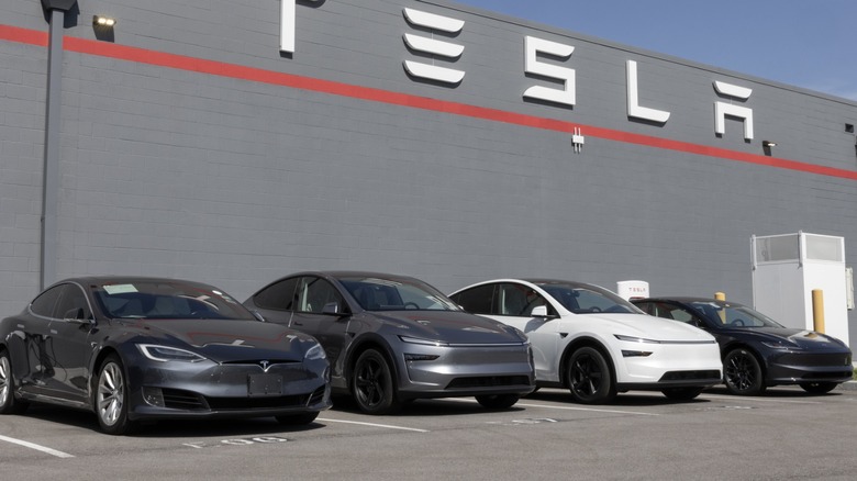Tesla cars parked outside a building with a large Tesla logo