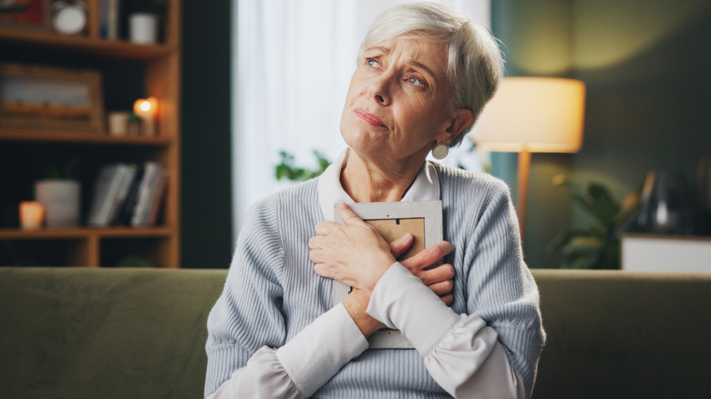 Sad elderly woman clutching photo