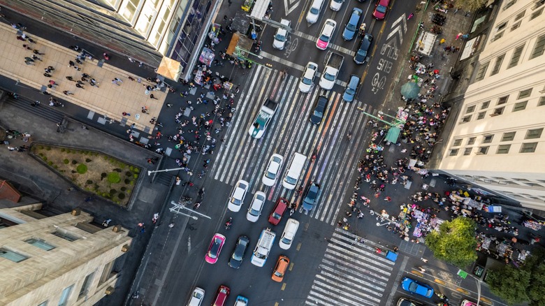 Aerial view of busy city intersection with heavy traffic, crosswalks, and crowds of pedestrians on surrounding sidewalks