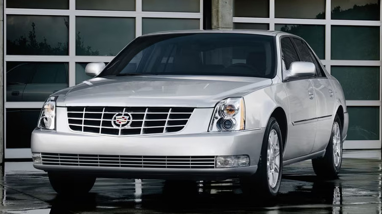 A white Cadillac DTS parked at an angle in front of a garage.