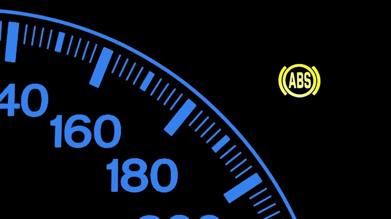 Car dashboard speedometer with illuminated ABS warning indicator