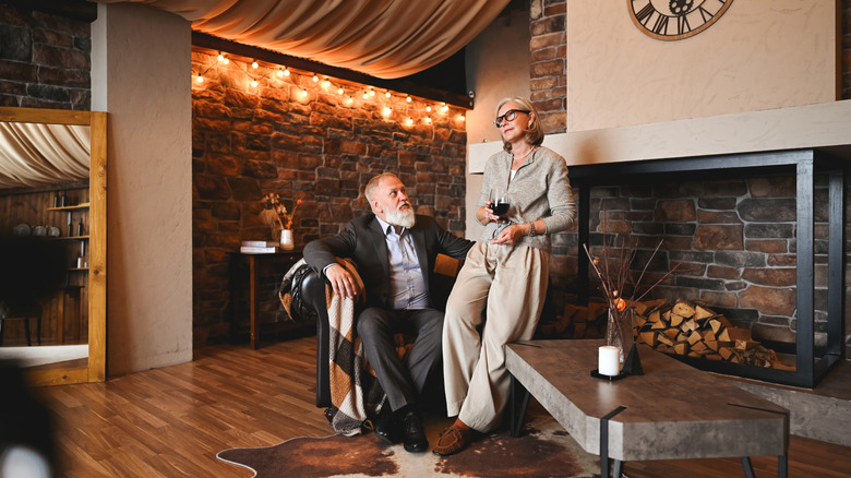 A stylish upper-class senior couple enjoying a glass of wine in their home