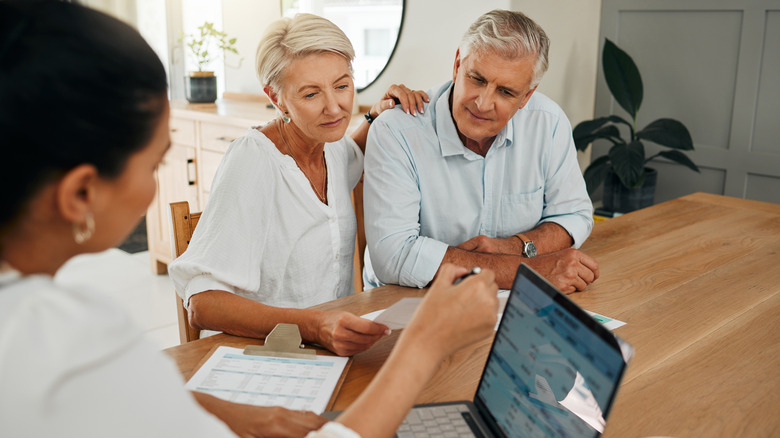 A financial advisor guiding a mature couple through their investment portfolio.