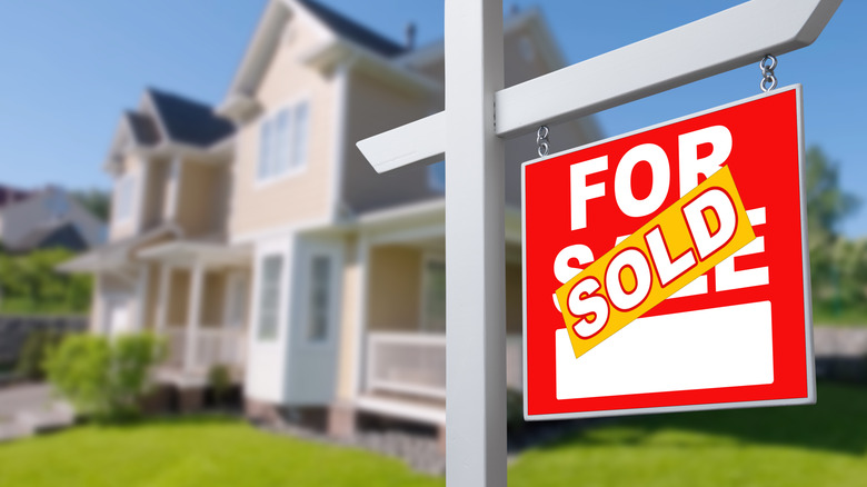 For sale sign in front of a house with a sold sticker