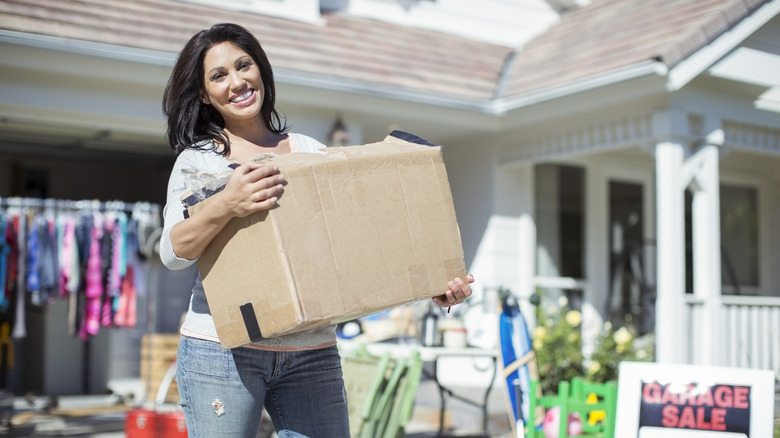 A smiling woman setting items out at a garage sale