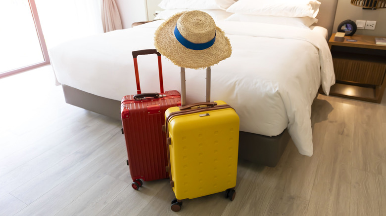 A bed with suitcases and a hat.