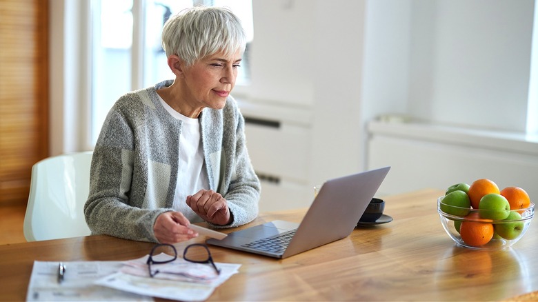 Person at laptop, holding card