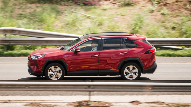 A red Toyota RAV4 driving fast on a highway.