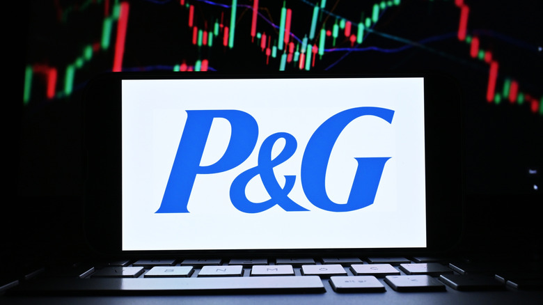 P&G logo on phone with stock market chart in background