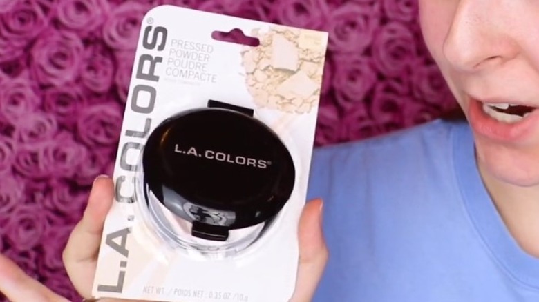 Woman holding unopened L.A. Colors pressed powder product