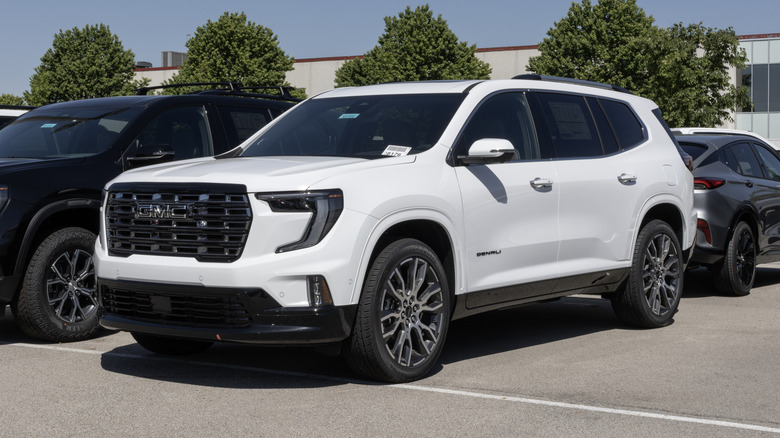 A white GMC Acadia Denali Ultimate AWD SUV at a dealership.
