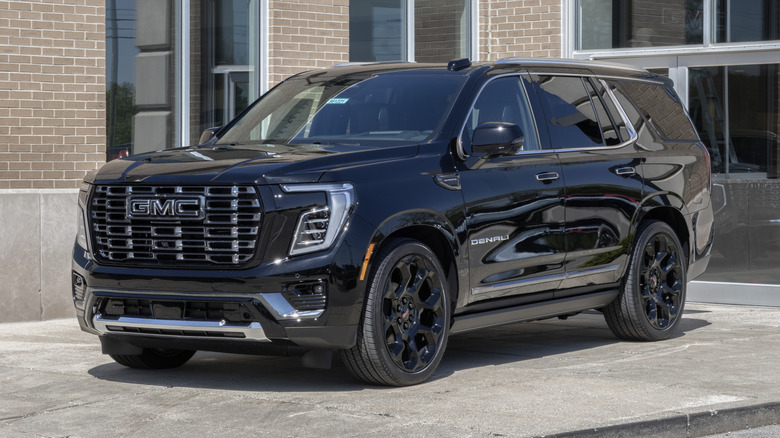 A black GMC Yukon 4WD Denali Ultimate SUV at a dealership.