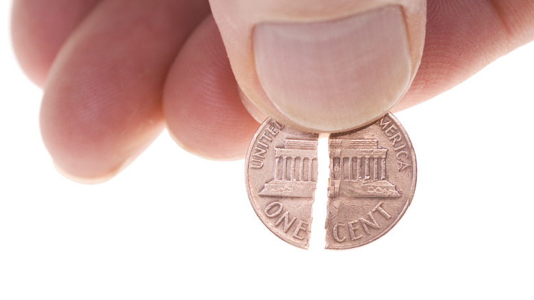 Close-up of a hand holding a broken penny.