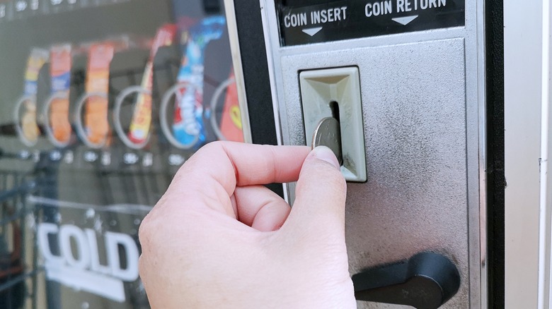 A woman is using a vending machine to purchase a snack.