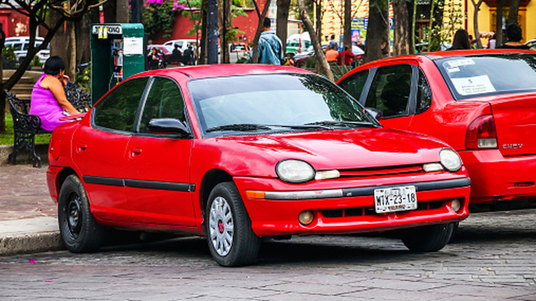 A red Plymouth neon parked on the street.