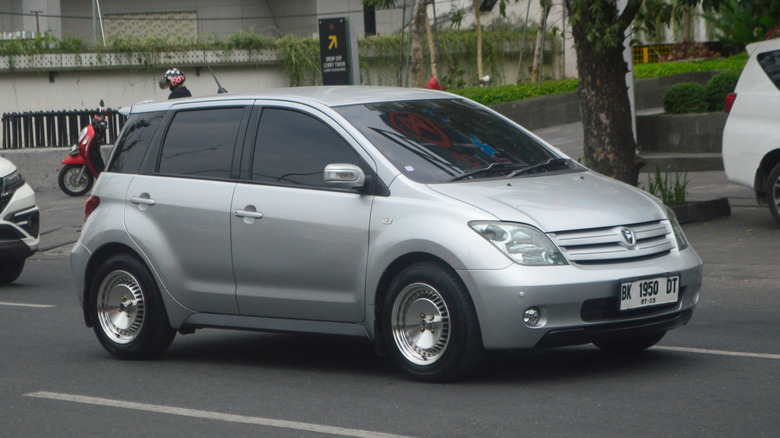 A silvet Toyota Ist (Scion xD) being driven on the street