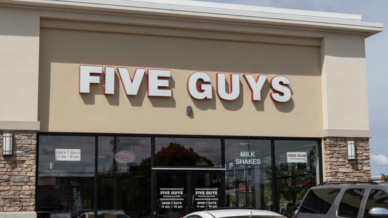 Front of a Five Guys restaurant with cars