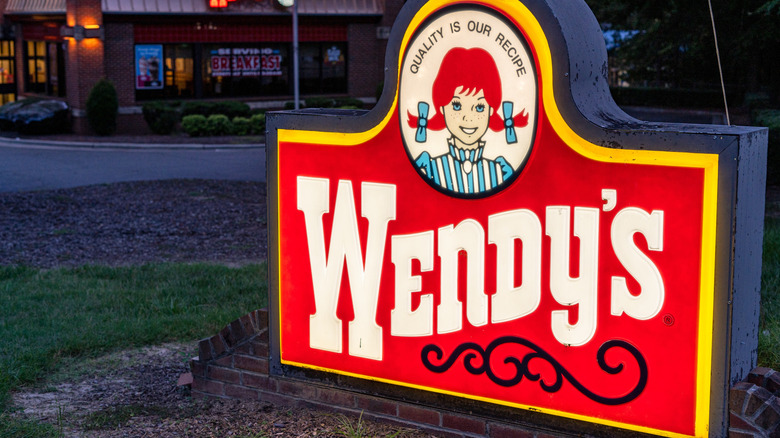 Close up shot Wendy's ground sign near entrance, lit up at night