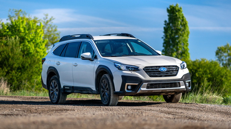 A white Subaru Outback all-terrain car off-roading.