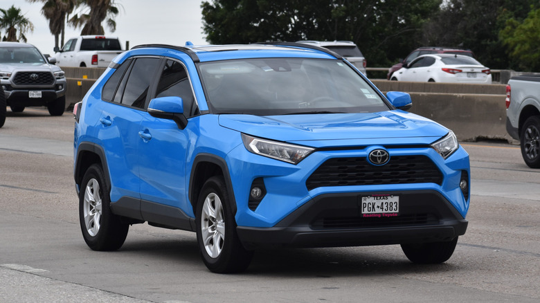 A blue Toyota Rav 4 traveling down a highway in moderate traffic