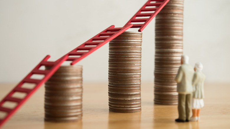 An old senior couple looking at growth stack coins graph chart with red ladder.