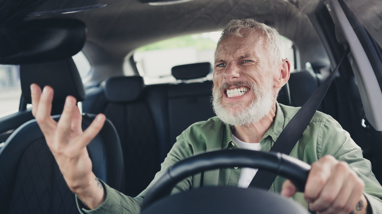 Photo of irritated annoyed seniour guy wear green shirt driving car shouting outdoors urban city street.