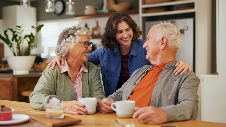 Senior father and old mother sharing tea and heartfelt conversation with daughter at home at tea time.