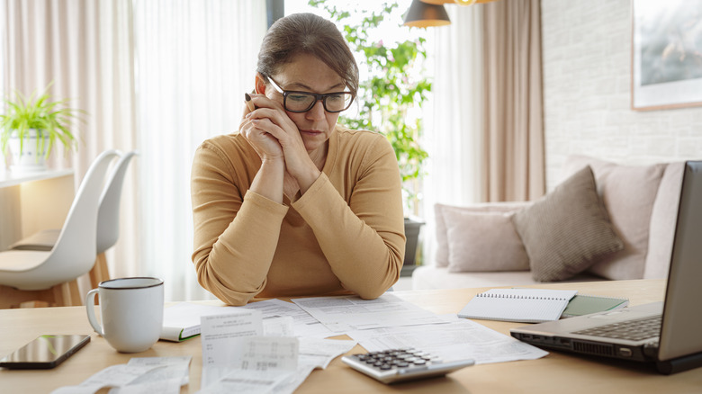 Mature woman contempling bills and tax papers at home.