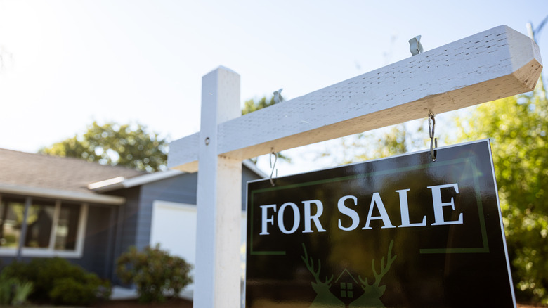 Close up of "for sale" sign in front of home