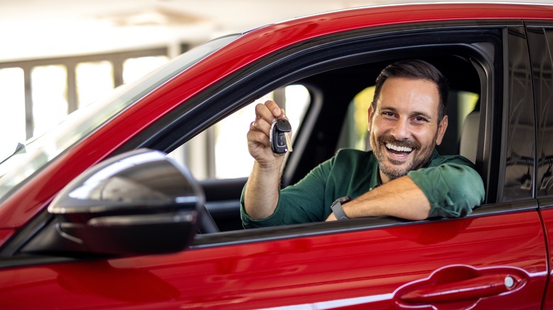 man sitting in a new car smiling