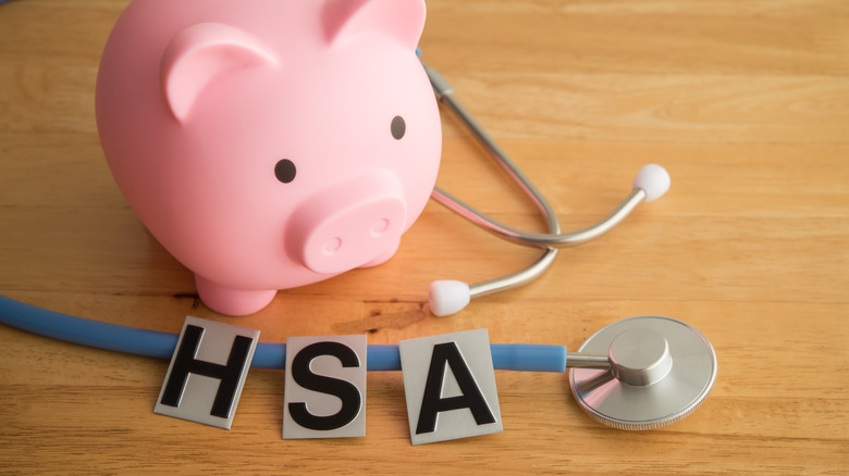 A piggy bank, stethoscope, and three plastic cutouts of the letters H, S, and A