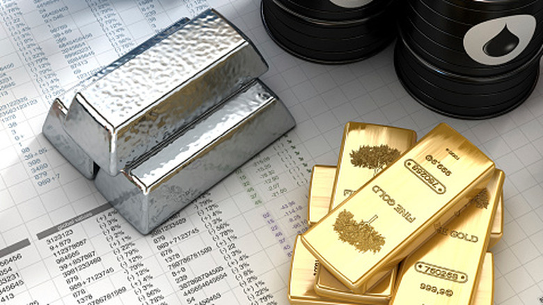 Three silver bars sit in stack next to pile of gold ingots