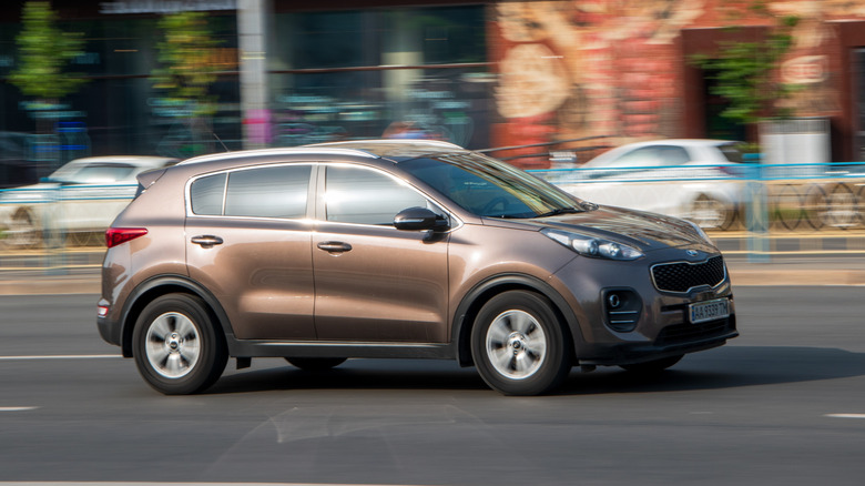 A brown KIA Sportage car moving on the street.