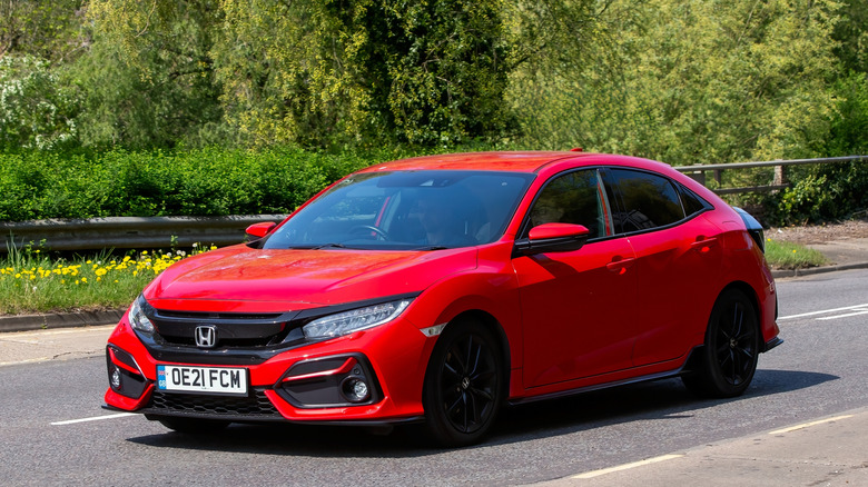 A red 2021 Honda Civic driving on an English road.