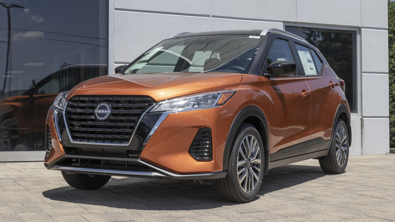 A burnt orange 2022 Nissan Kicks on display at a dealership.