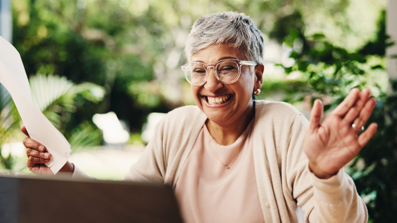 Senior, happy woman doing taxes on a laptop.