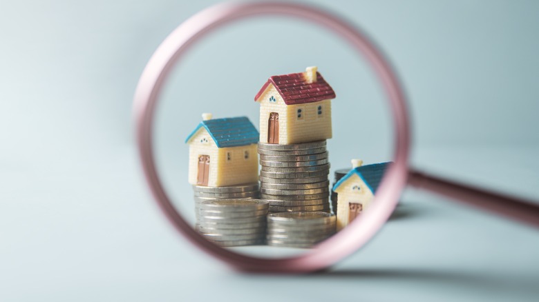 A magnified view of three small houses stacked on top of each other with coins on top of the houses.