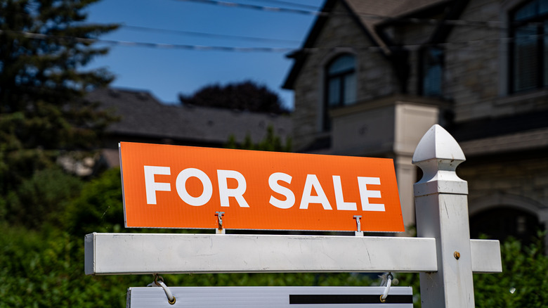 View of for sale sign in front of a house.