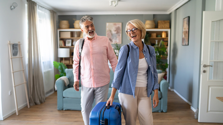 An older couple with luggage standing in a room.