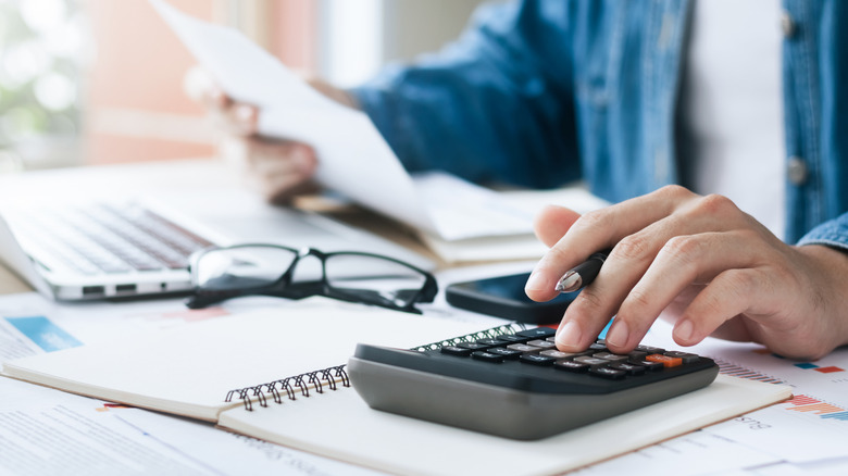 A person with their hand on a calculator doing taxes