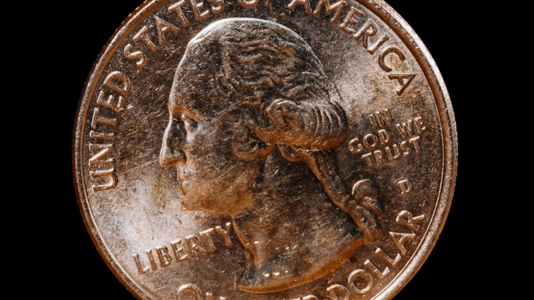 A brassy or golden-tinted quarter up close with visible scratch marks on it.