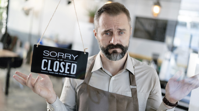 A man standing near a 'closed' sign