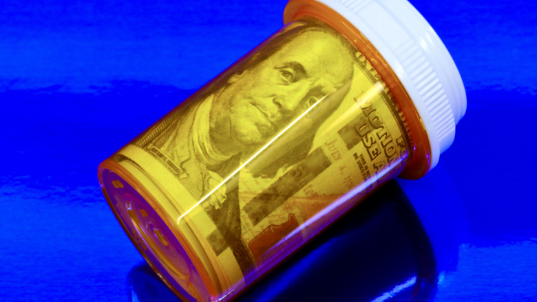 A Benjamin Franklin-faced $100 bill rolled up in a yellow transparent pill bottle
