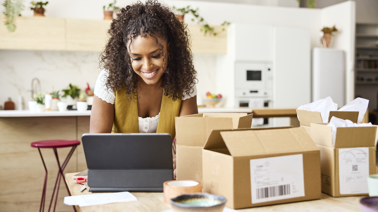 Young woman at table with tablet and boxes